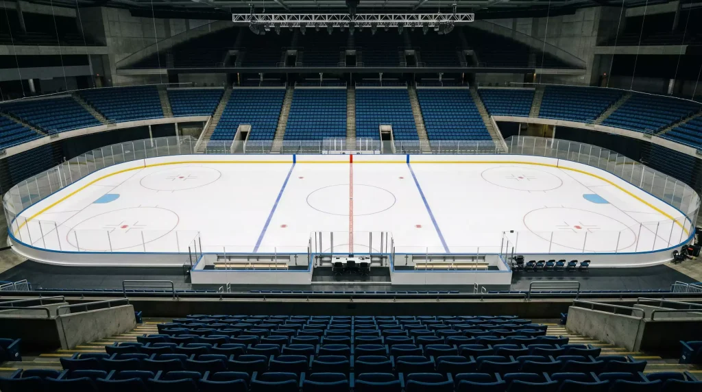 Leere Eishockey-Arena von der oberen Tribüne aus gesehen mit hell beleuchteter Eisfläche und unbesetzten Sitzreihen