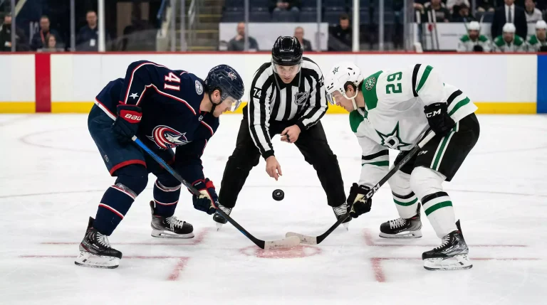 Zwei NHL-Spieler stehen sich im Bully in der Mitte des Eises gegenüber mit Schiedsrichter und Puck