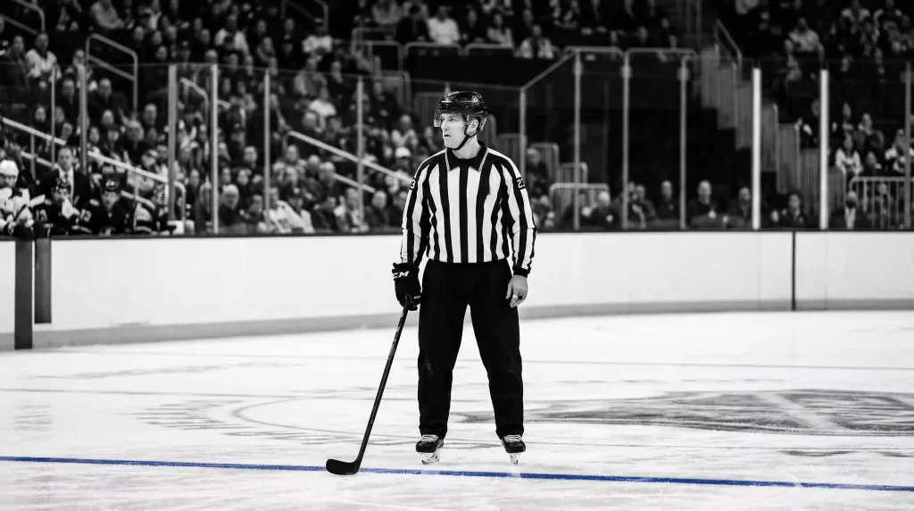 NHL-Schiedsrichter im gestreiften Trikot steht auf der Eisfläche während eines Spiels