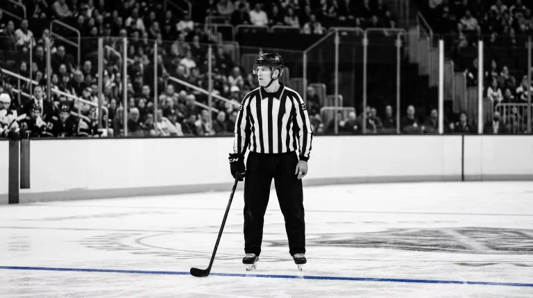 NHL-Schiedsrichter im gestreiften Trikot steht auf der Eisfläche während eines Spiels